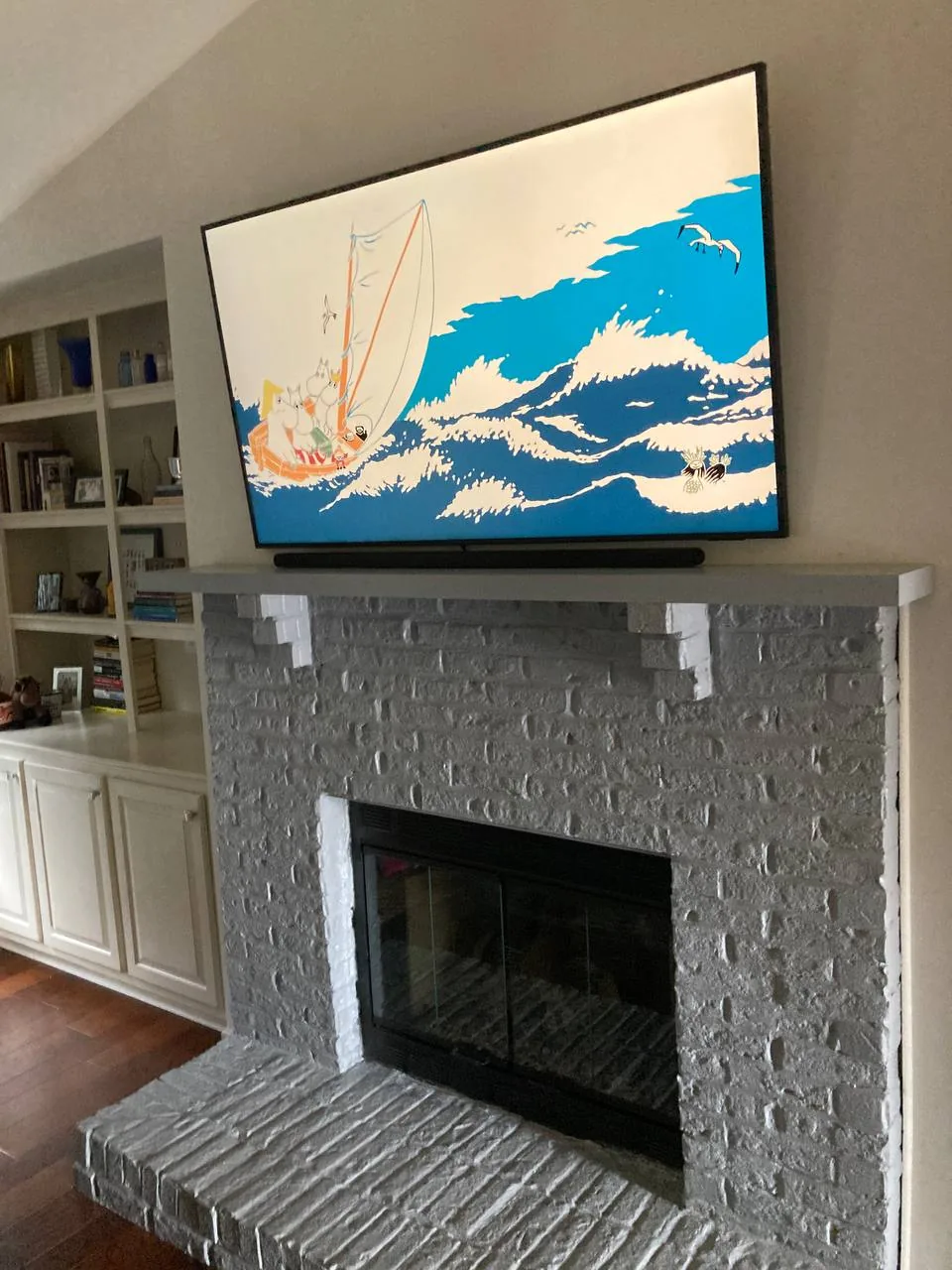Samsung Frame TV mounted flush over brick fireplace with soundbar and custom built-in shelving